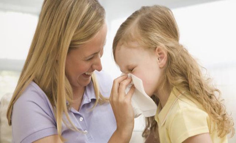 Adult helping child blow their nose